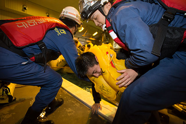 着岸したスライドラフトから乗客を抱え上げる消防隊員＝2月18日 PHOTO: Tatsuyuki TAYAMA/Aviation Wire