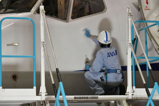 羽田空港の格納庫でANAウイングス創立10周年デカール貼付前に737-800 JA89AN を拭く整備士＝20年9月23日 PHOTO: Tadayuki YOSHIKAWA/Aviation Wire