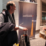 羽田空港でパリ行きAF293便の乗客に記念品を手渡すエールフランス航空の係員（同社提供）